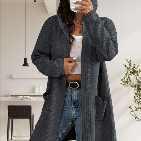 Person wearing a long dark gray coat in a modern interior setting